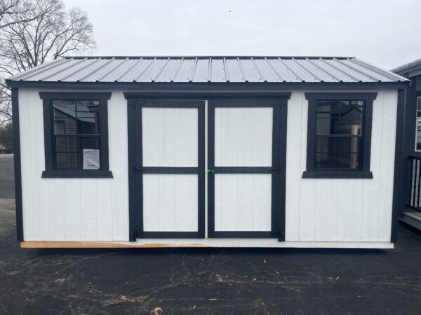 A Frame Shed. White with Black Trim. 2 Windows and a door.